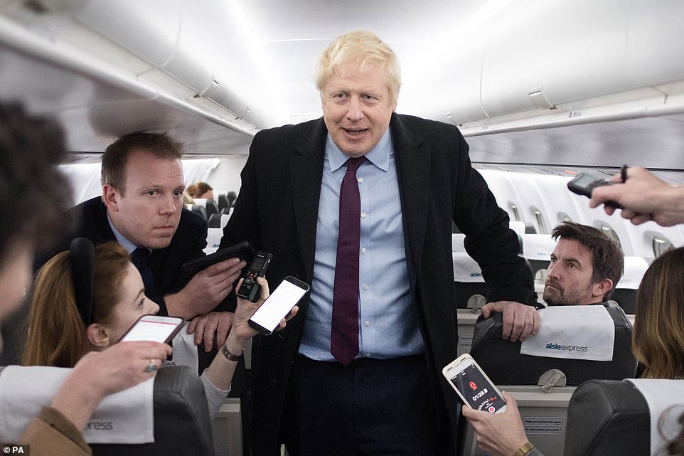 Boris Johnson speaks to reporters on the plane on the final day of campaigning. Beside him is his head of press Rob Oxley (left) who swore live on television this morning when the PM was confronted by an ITV reporter