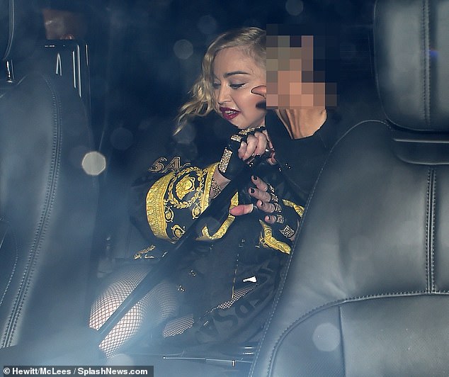 Cheeky! With her tresses worn in its naturally curly state, Madonna accentuated her youthful-looking complexion with her trademark red lipstick, with her partner flashing up a rude sign