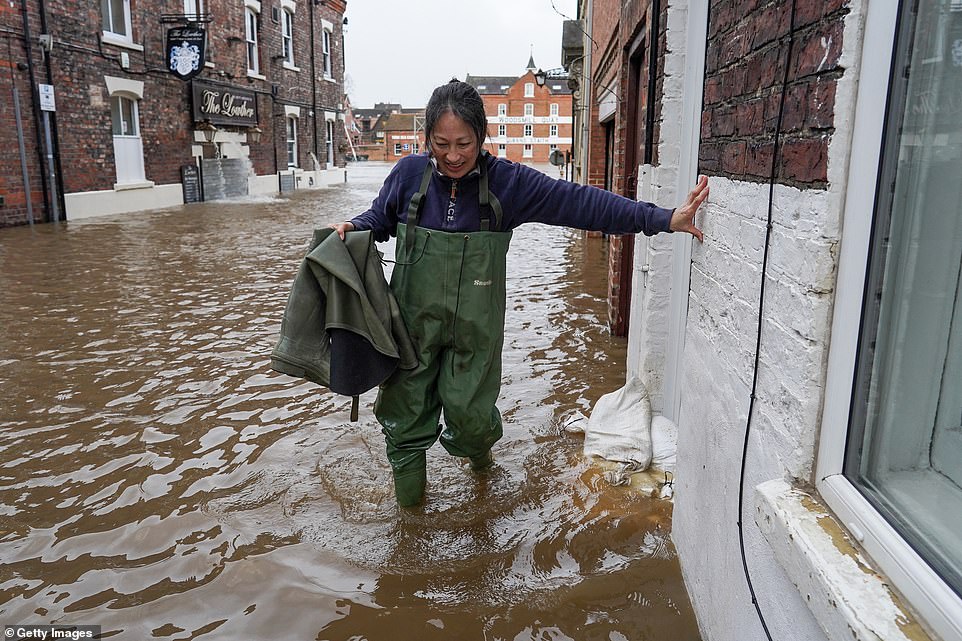 A woman makes her way through flood water as the waters of the River Ouse passing through York breach the river banks yesterday