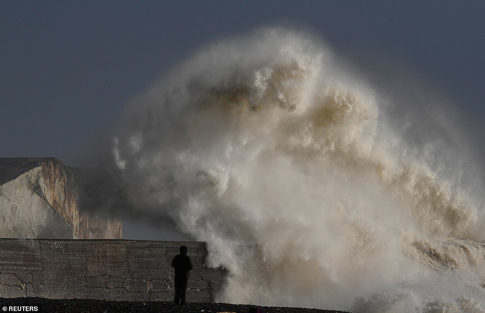 A man views large waves as they hit the harbour wall at Newhaven this afternoon. He was prepared for the weather though and can be seen looking at the wave wearing his waterproof hood