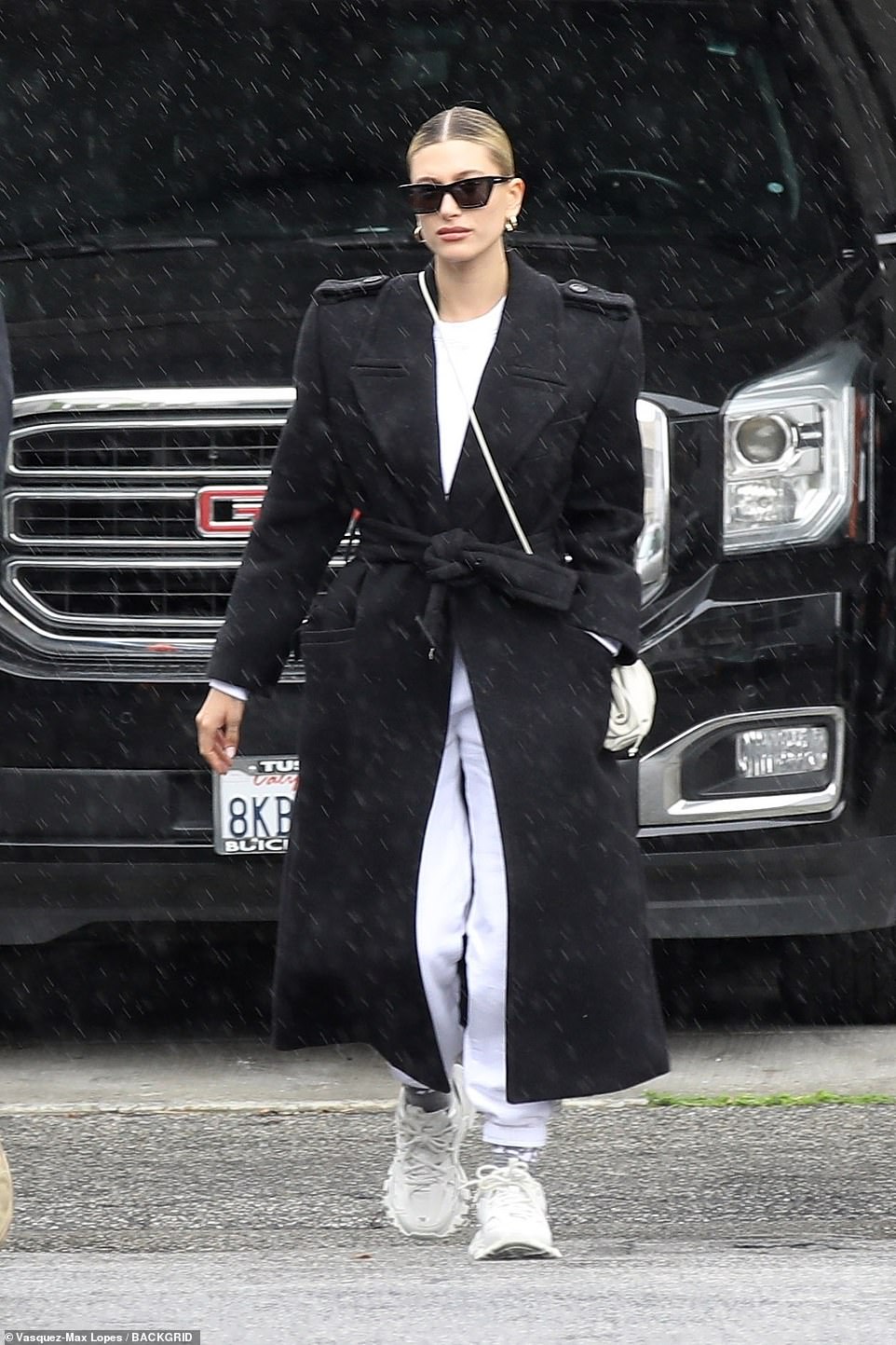 Worth it: Hailey Baldwin was seen braving the rainy weather in a long black coat to check out Madonna's old mansion in Beverly Hills on Tuesday morning