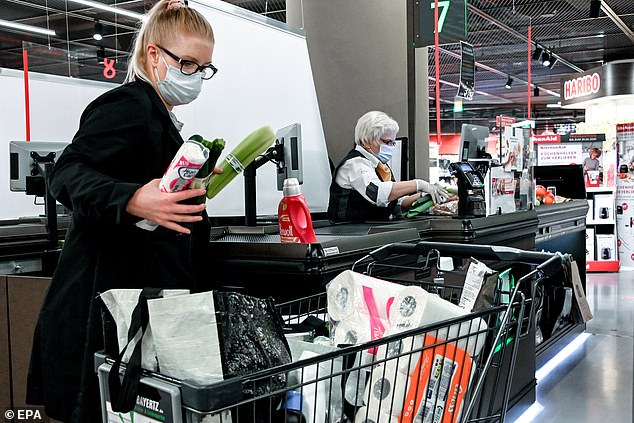 Some countries have begun to re-open shops (a customer is seen here shopping in Germany yesterday), but economists expect a worse economic slump in Q2