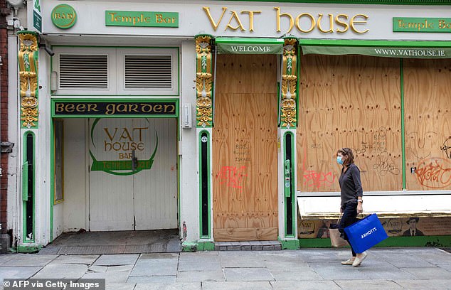 But Ireland's multinational export sector has a warping effect on the headline GDP figure of the nation - home to five million people. Modified domestic demand - a figure that strips out the effects of multinationals - registered a 5.4-percent slump in 2020. Pictured: A woman walks past a boarded up bar in Dublin amid the coronavirus pandemic