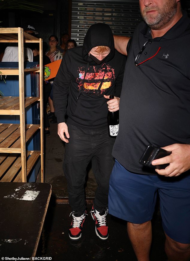 Ducking out: Ed Sheeran, 30, cut a low-key figure when he left Scooter Braun's star-studded party in NYC, obscuring his face with a black hood and facemask