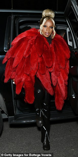 Lady in red: The Just Fine singer, 50, wore a ruby red fur coat with the design taking on a feathered form teamed with a pair of form-fitting leather trousers, as she stepped out to the star-studded fashion event