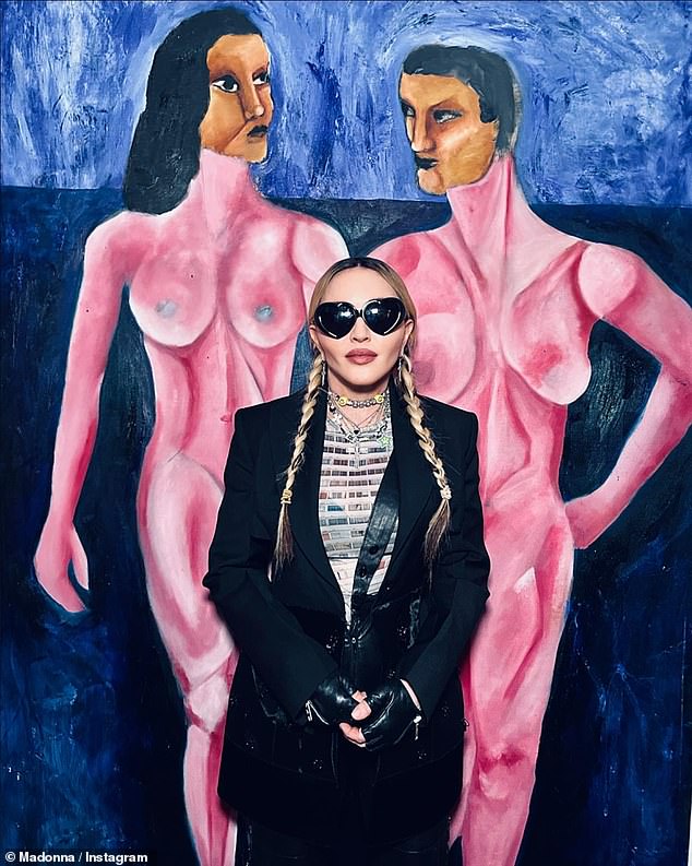 Looking good: The Open Your Heart artist was seen donning pigtails with her hair parted and a pair of black slacks on the outing, in which she posed in front of a number of his paintings