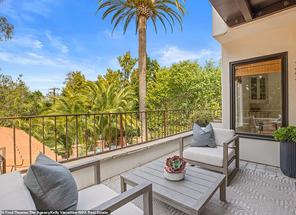 The three-story home comes complete with white stucco and a terracotta-roof structure that is accentuated with a soaring stone turret that features a Gothic-arch wood front door.