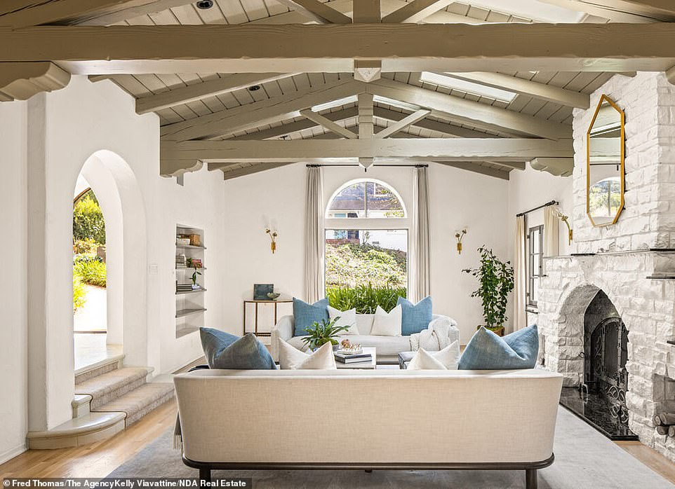 Once inside, the entrance opens into a tiled foyer that leads into a sunken living room, in which the centerpiece is a whitewashed stone fireplace along with an adjacent sitting area that overlooks the stunning outdoor grounds.