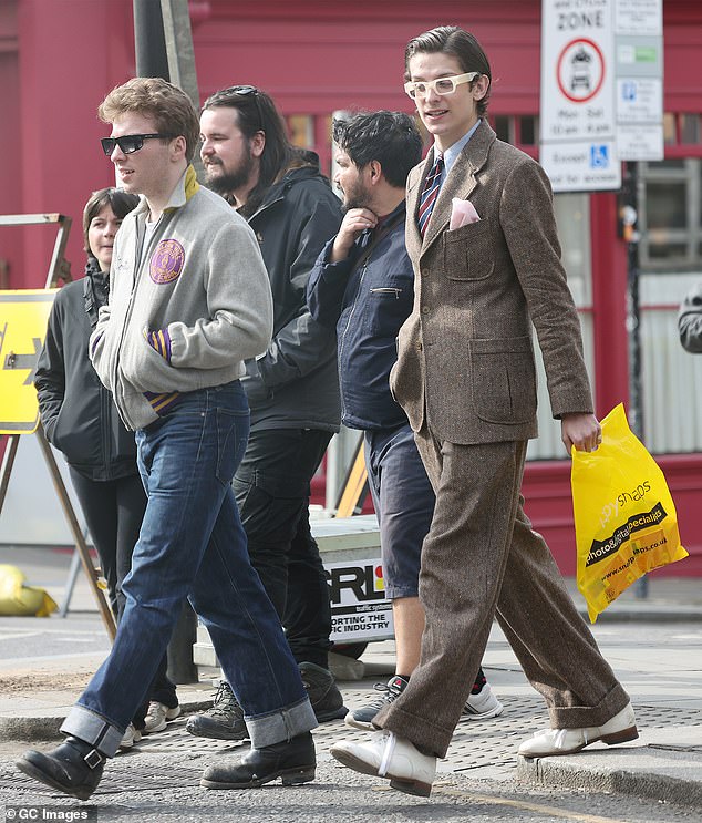 Meanwhile his dapper friend turned heads with his retro fashion sense stepping out in a brown tweed suit and wore a pair of white framed sunglasses.