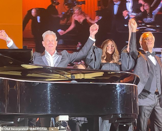 All the glory: Foster, McPhee and Bocelli triumphantly raised their hangs together after their performance, which was greeted with a loud applause by the audience