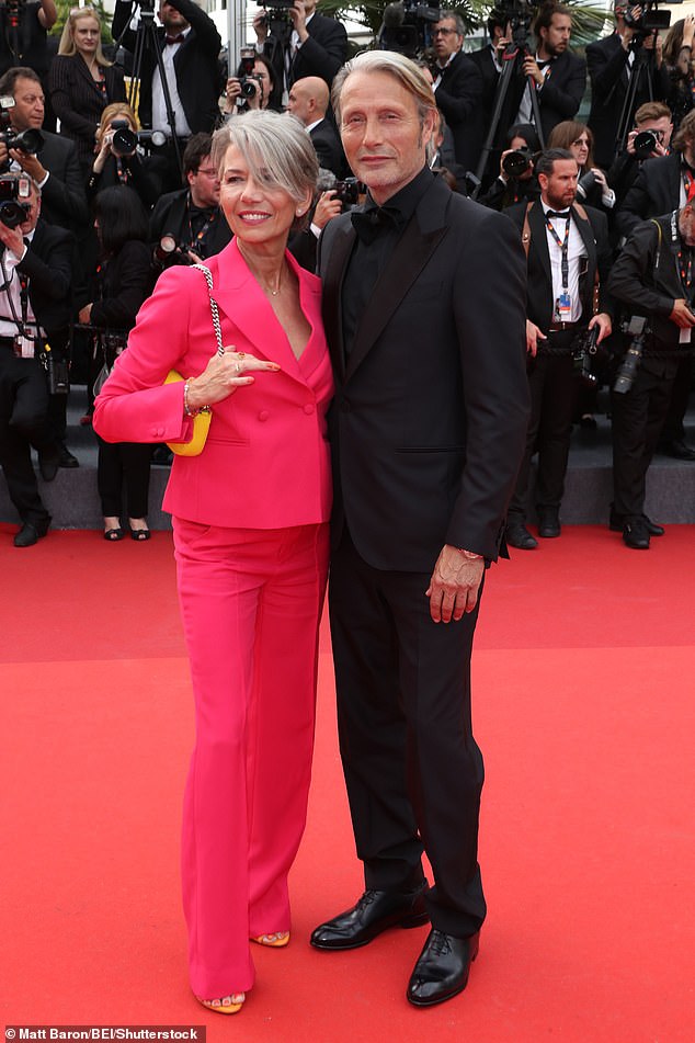 Cute couple: Meanwhile Mads donned an all black ensemble as he attended alongside wife Hanne Jacobsen, who stunned in a bright pink tailored suit