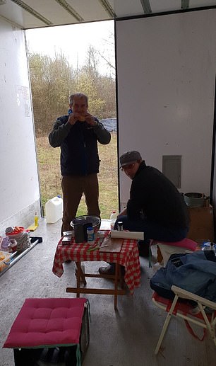 Ionut, sitting, shares a meal with a fellow truck driver