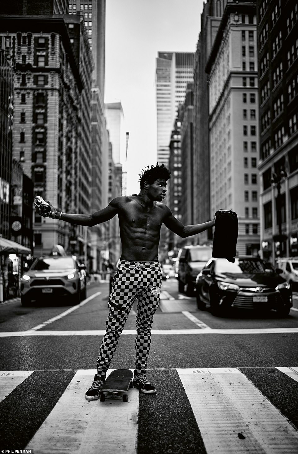 A skateboarder on 5th Avenue sports checkered pants while standing on a pedestrian cross