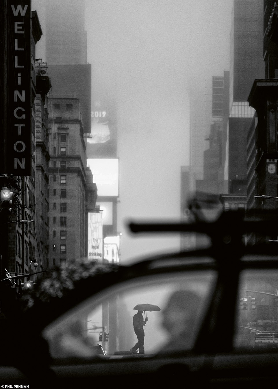 A man walks with an umbrella overhead on a foggy day in midtown Manhattan in June, 2019