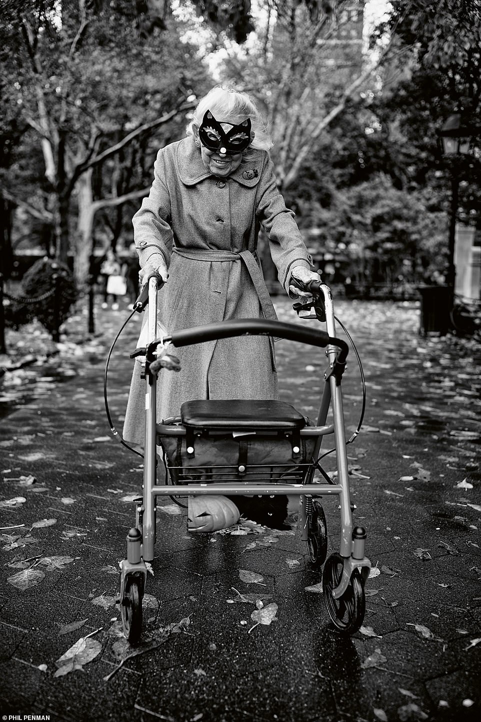 An elderly woman wearing a dress-up mask stops to pose for a photo on Halloween night at Washington Square Park in October, 2019