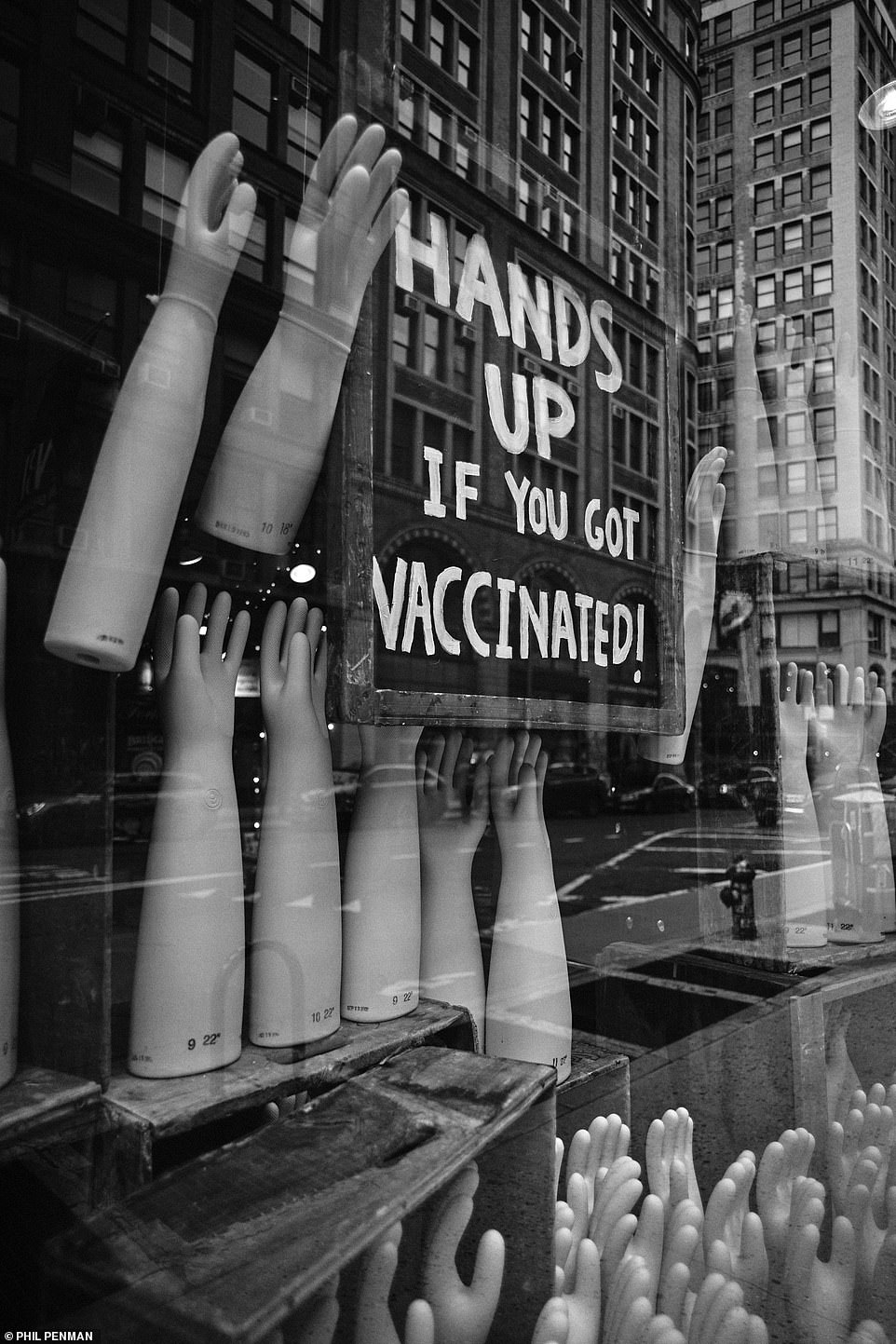 A sign hangs in a window display on Broadway, New York City, saying: 'hands up if you're vaccinated'