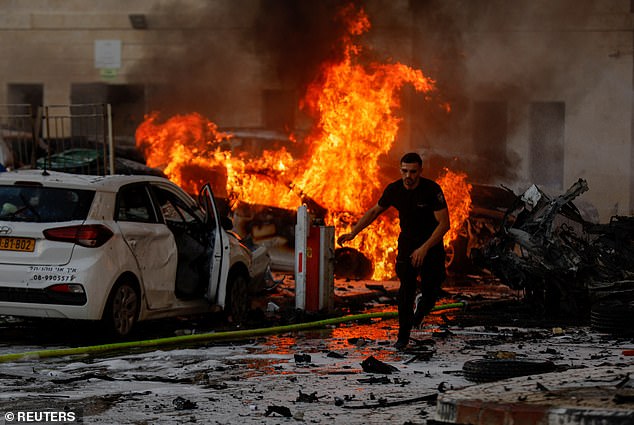 A man runs in the road as fires burn in Ashkelon, Israel, following rocket attacks from the Gaza Strip initiated by Islamic militant group Hamas