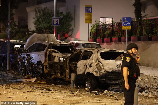 A member of the Israeli security forces stands along a debris-strewn street in Tel Aviv