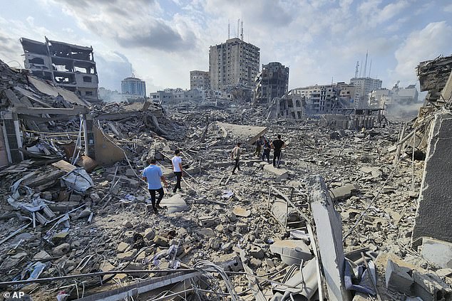 Palestinians walk through the rubble of buildings hit by Israeli airstrikes in Gaza on Tuesday