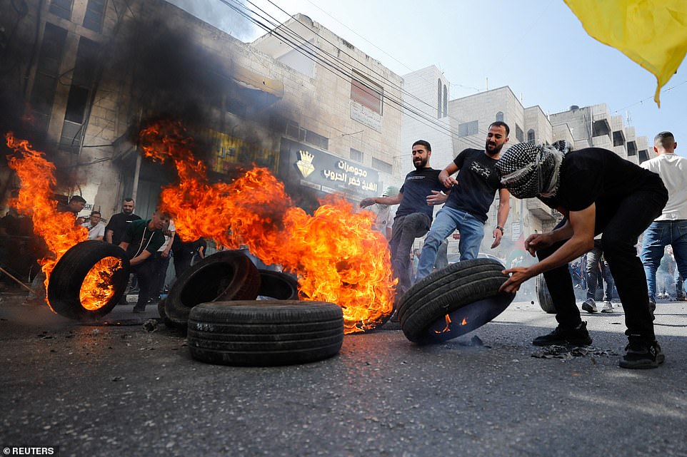 WEST BANK: Protesters stand near burning tires as Palestinians take part in a protest following Israeli strikes on Gaza, in Hebron, in the Israeli-occupied West Bank on Friday