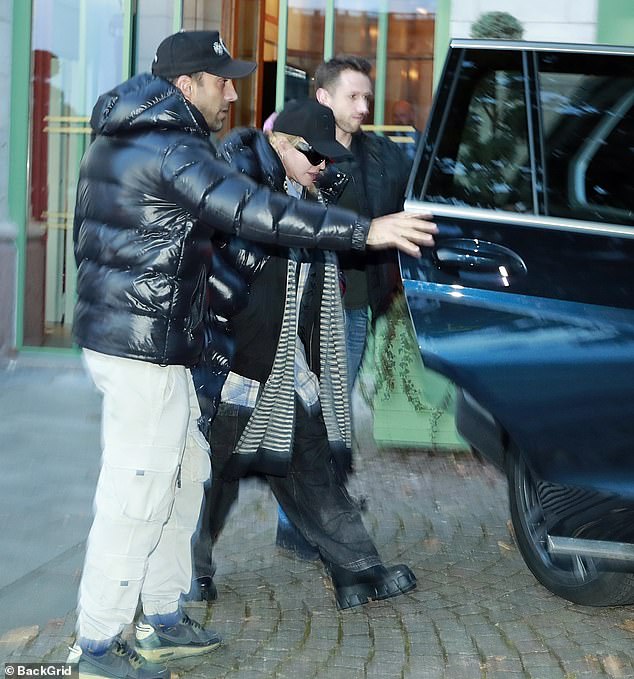 Getaway: She wore a chunky striped scarf around her shoulders and a black baseball cap as she made her way to a waiting car