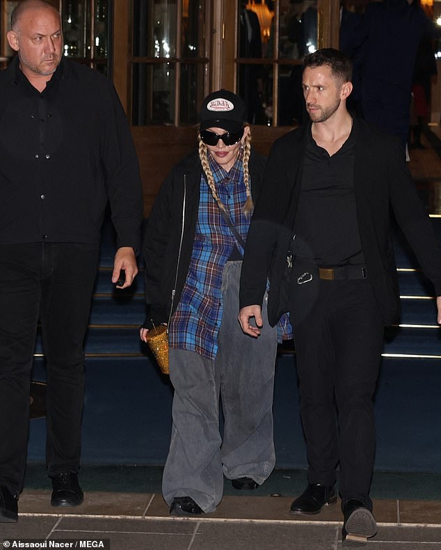 Gotta stay hydrated: Madonna completed her look with chunky black trainers and held a gold cup in her hand, her hair styled in its signature two plaits