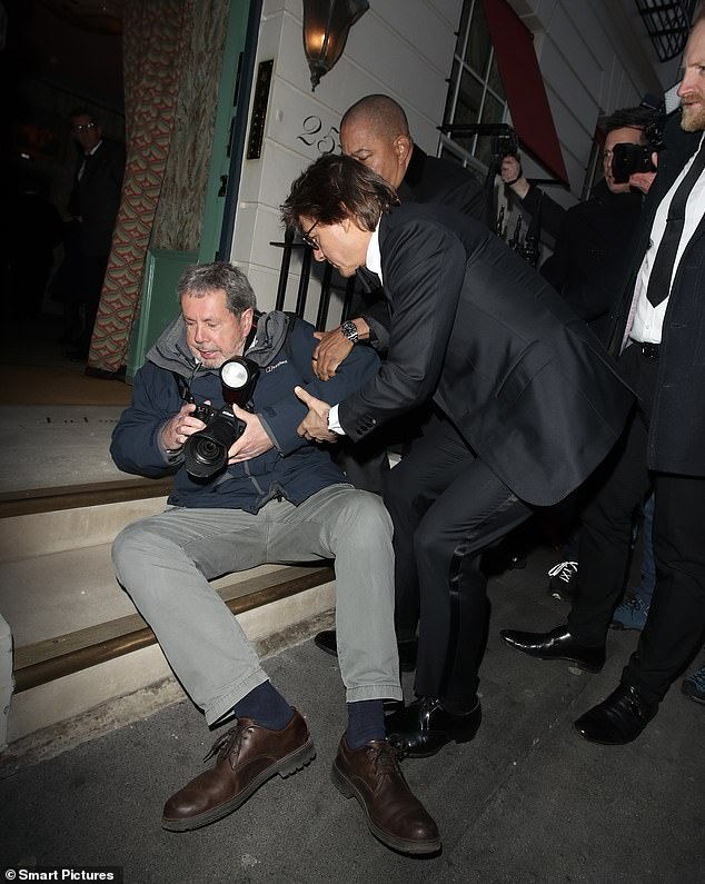 Tom Cruise stopped to help up a photographer who crashed to the ground as the movie star arrived at Victoria Beckham's 50th birthday party on Saturday