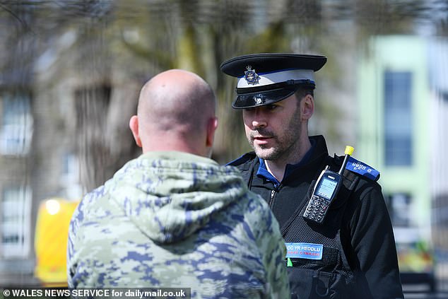 Police speak to a man outside the school on Wednesday following the incident at Amman Valley School in Carmarthenshire