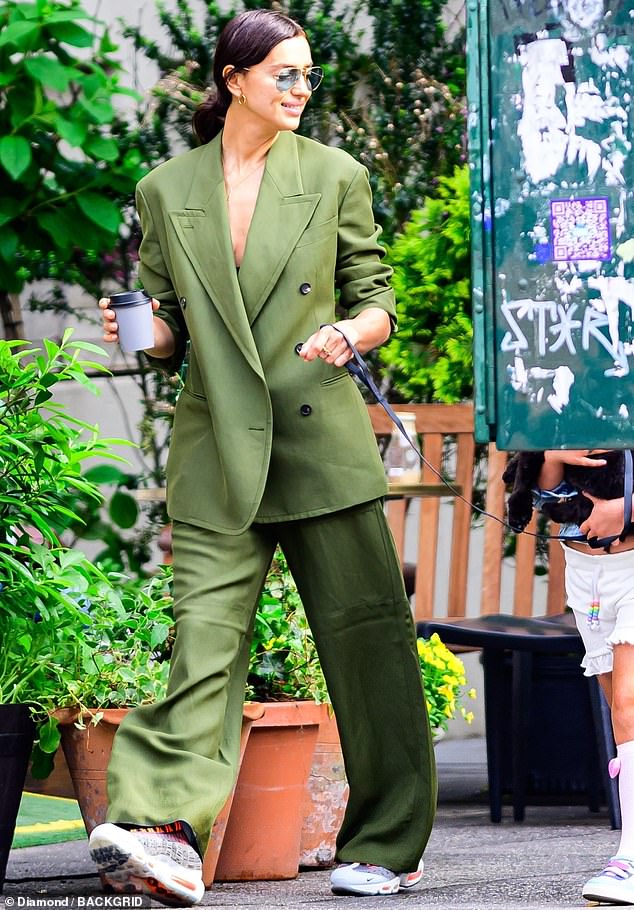 For her latest sighting, Irina cut a stylish figure in a trendily loose-fitted moss green trouser suit with its sleeves rolled up in light of the rising summer temperatures