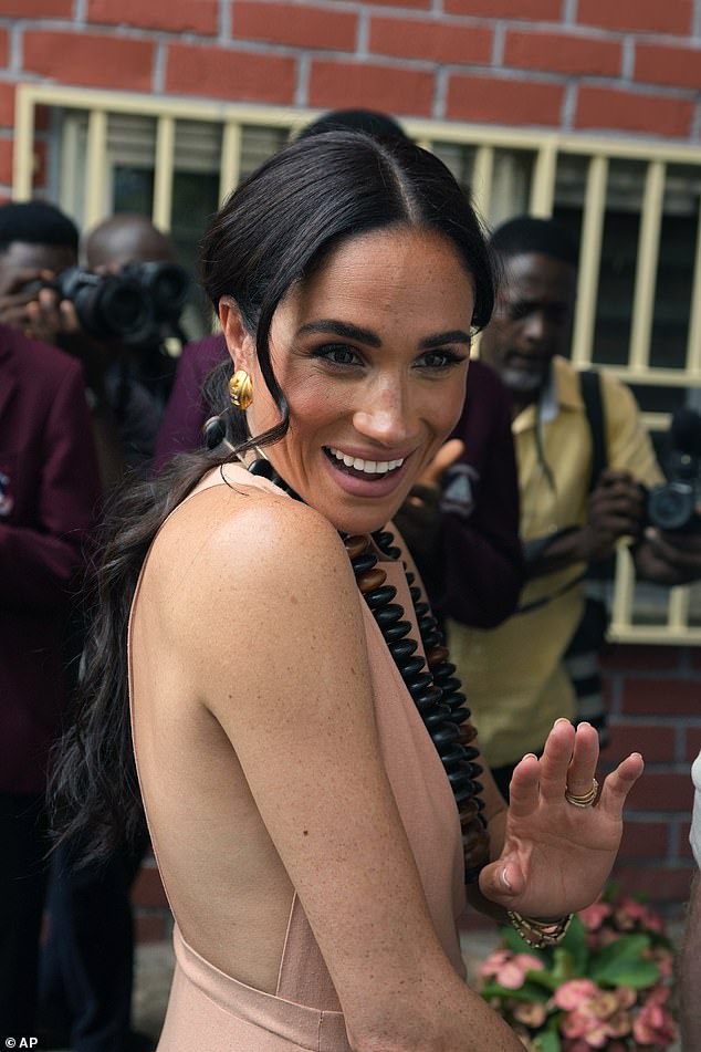 Meghan Markle gestures as she and Prince Harry visit children at a school in Abuja on May 10