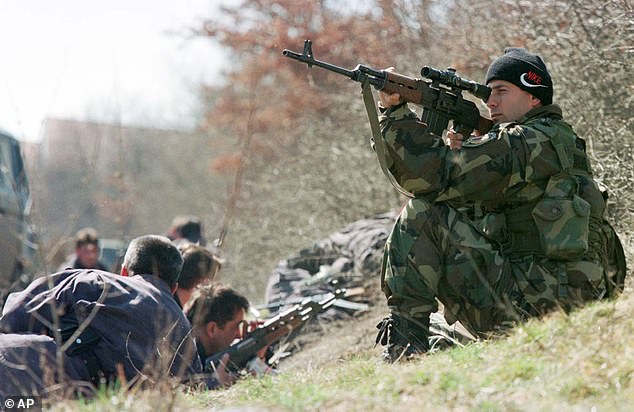 A Serbian policeman takes a look through the sight of his rifle in March 22, 1999