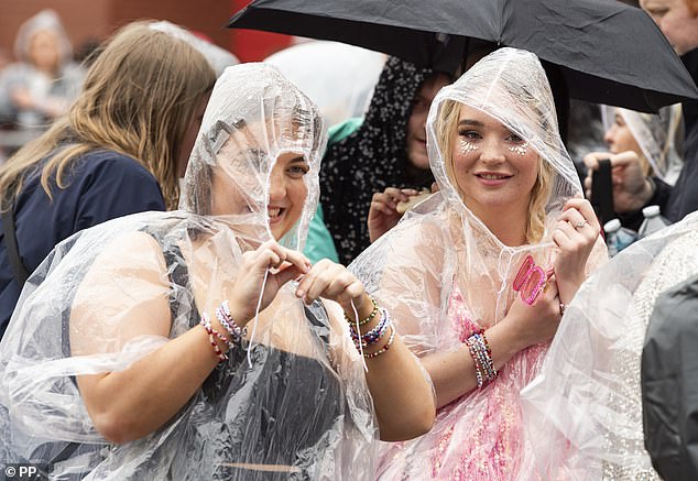 Two Taylor Swift fans brave the rain and wear ponchos to protect their themed outfits