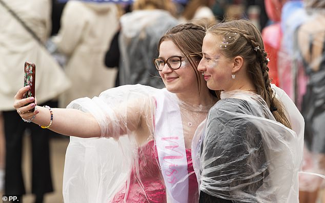 Two fans pose for a selfie as they wear ponchos to protect themselves from the rain