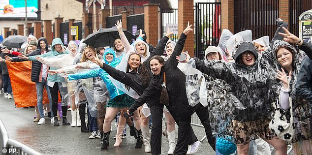 Several Taylor-Swift themed ponchos can be seen as fans brave the rain outside the stadium