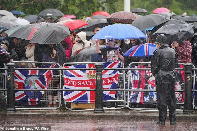 Royal fans wait in heavy rain on the Mall for the return of the royal procession today