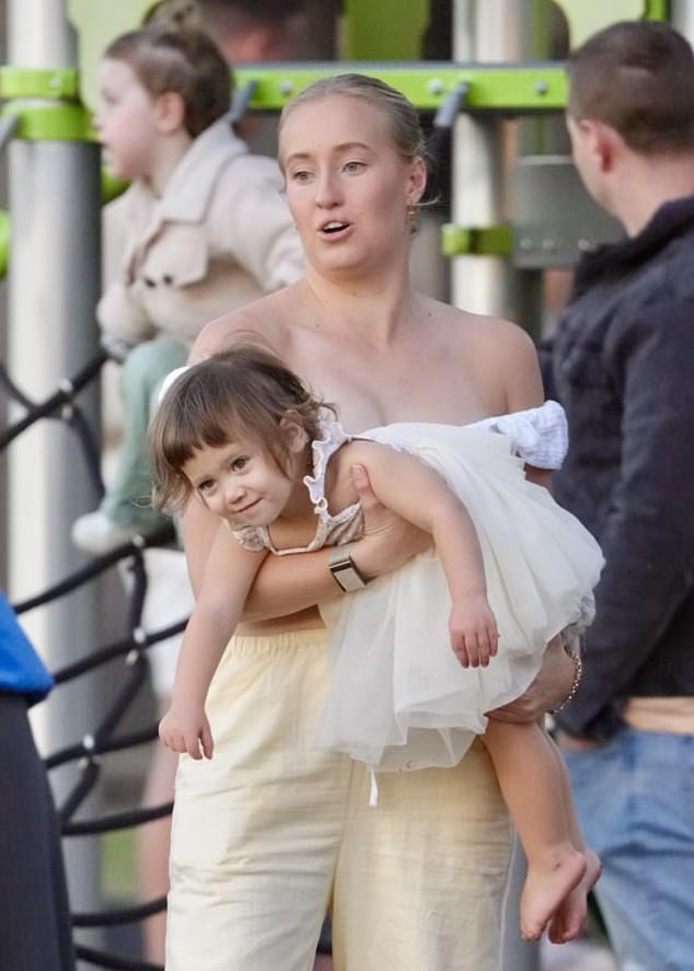 A family friend carried the toddler, who was dressed in a sweet cream frock