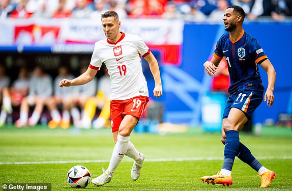 HAMBURG, GERMANY - JUNE 16: Przemyslaw Frankowski of Poland and Cody Gakpo of Netherlands battle for the ball during the UEFA EURO 2024 group stage match between Poland and Netherlands at Volksparkstadion on June 16, 2024 in Hamburg, Germany. (Photo by Mateusz Slodkowski/Getty Images)