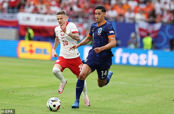 epa11415195 Tijjani Reijnders of the Netherlands in action against Sebastian Szymanski (L) of Poland during the UEFA EURO 2024 group D match between Poland and Netherlands, in Hamburg, Germany, 16 June 2024.  EPA/ABEDIN TAHERKENAREH