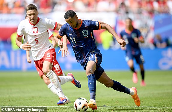 HAMBURG, GERMANY - JUNE 16: Cody Gakpo of the Netherlands runs with the ball whilst under pressure from Jan Bednarek of Poland during the UEFA EURO 2024 group stage match between Poland and Netherlands at Volksparkstadion on June 16, 2024 in Hamburg, Germany.   (Photo by Stuart Franklin - UEFA/UEFA via Getty Images)