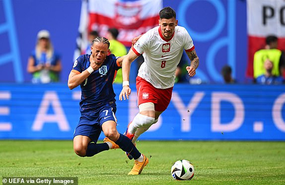 HAMBURG, GERMANY - JUNE 16: Jakub Moder of Poland runs with the ball whilst under pressure from Xavi Simons of the Netherlands during the UEFA EURO 2024 group stage match between Poland and Netherlands at Volksparkstadion on June 16, 2024 in Hamburg, Germany.   (Photo by Stuart Franklin - UEFA/UEFA via Getty Images)