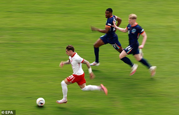 epa11415375 Nicola Zalewski of Poland (L) in action against Denzel Dumfries of the Netherlands (C) and Jerdy Schouten of the Netherlands during the UEFA EURO 2024 group D match between Poland and Netherlands, in Hamburg, Germany, 16 June 2024.  EPA/CLEMENS BILAN