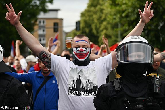 Soccer Football - Euro 2024 - Fans gather before Serbia v England - Gelsenkirchen, Germany - June 16, 2024 Police officers and a Serbia fan with face paint in the street ahead of the match REUTERS/Jana Rodenbusch