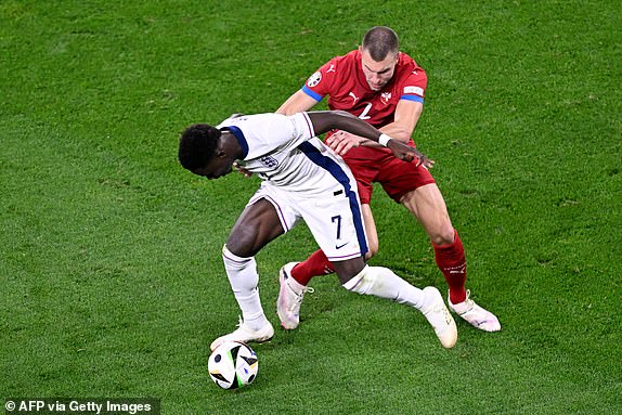 TOPSHOT - Serbia's defender #02 Strahinja Pavlovic fights for the ball with England's forward #07 Bukayo Saka during the UEFA Euro 2024 Group C football match between Serbia and England at the Arena AufSchalke in Gelsenkirchen on June 16, 2024. (Photo by INA FASSBENDER / AFP) (Photo by INA FASSBENDER/AFP via Getty Images)