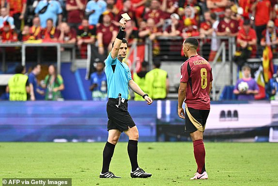 Turkish referee Umut Meler (L) gives a yellow card to  Belgium's midfielder #08 Youri Tielemans  during the UEFA Euro 2024 Group E football match between Belgium and Slovakia at the Frankfurt Arena in Frankfurt am Main on June 17, 2024. (Photo by JAVIER SORIANO / AFP) (Photo by JAVIER SORIANO/AFP via Getty Images)