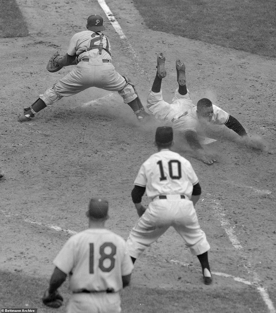 Willie Mays of the New York Giants dives into home plate safely here in the sixth inning of an extra-innings loss to the Phillies