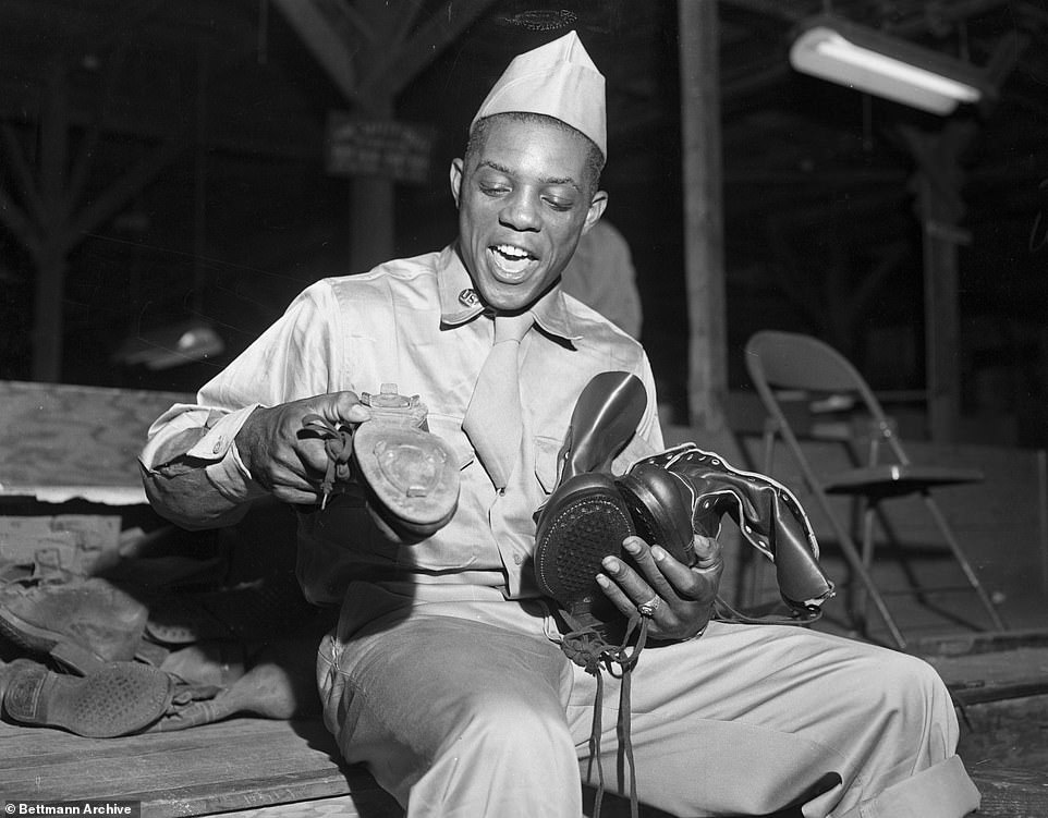 Army rookie Willie Mays, outfielder for the NY Giants, ruefully bids goodbye to his spiked baseball shoes in 1952