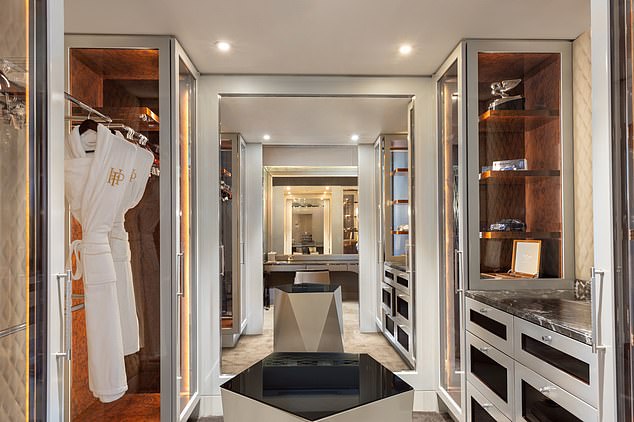 The enormous walk-in closet, replete with glass-cased his and hers wardrobe areas and a large dressing table facing a wall-to-wall mirror