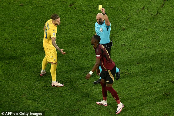 Polish referee Szymon Marciniak (R) gives a yellow card to  Belgium's forward #14 Dodi Lukebakio (down) during the UEFA Euro 2024 Group E football match between Belgium and Romania at the Cologne Stadium in Cologne on June 22, 2024. (Photo by Angelos Tzortzinis / AFP) (Photo by ANGELOS TZORTZINIS/AFP via Getty Images)