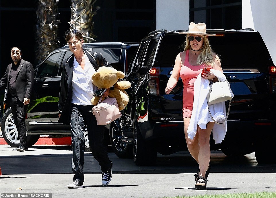 Britney completed her beach-ready ensemble with a black choker necklace, and she carried a white hoodie with a stain on one of the sleeves and a pale yellow handbag. She was accompanied by an assistant in casual black jeans and a black suit jacket who carried a large teddy bear for the hitmaker. Los Angeles is currently experiencing a heat wave, but Britney had her hoodie on during an initial air-conditioned SUV ride, but she stripped out of it as soon as she was back in the sun.