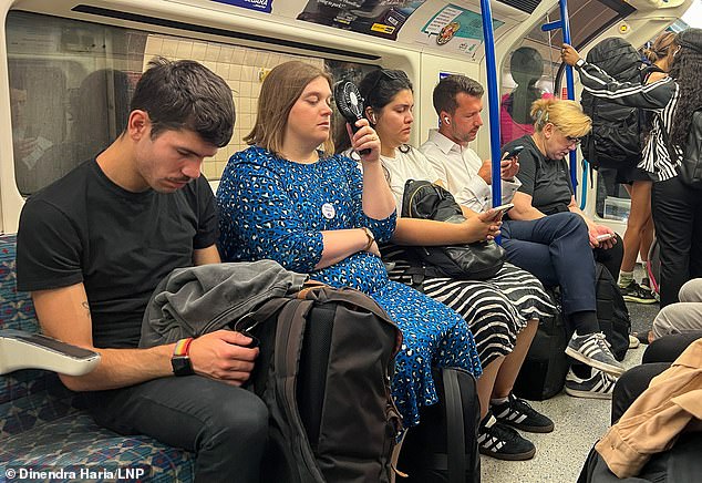 A woman with a handheld fan travelling on a hot London Underground train on Tuesday
